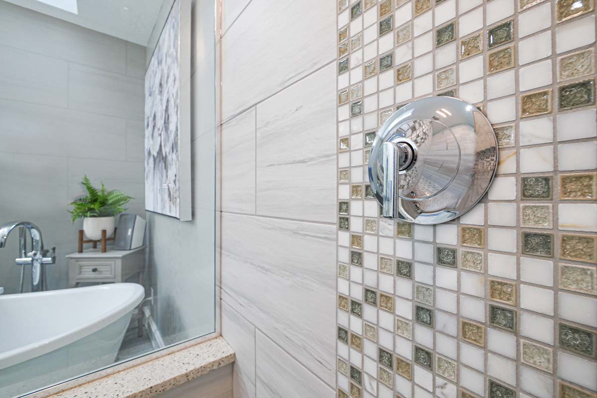 New bathroom with glass shower and beautiful tiled backsplash.