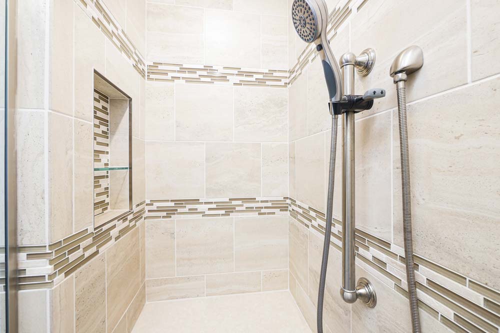 Beige tiled shower with a seat inside and easily accessible handles.