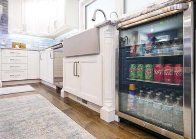 Open space kitchen with white cabinets and a mini-fridge with water, soda and dairy.