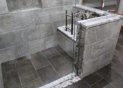 Wide tiled wheelchair accessible shower with a seat.