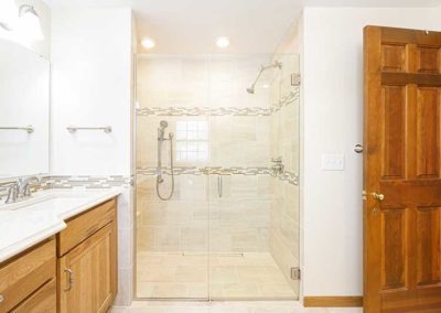Bathroom with a sink on the left and a wheelchair accessible shower with a seat on the right.