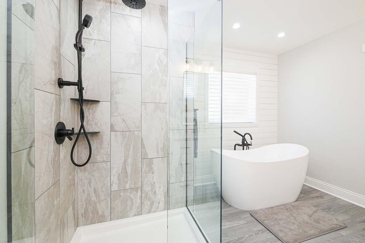 Brand new bathroom with a white bathtub and glass shower.