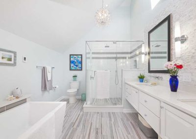 Bathroom with glass shower, bathtub, and white cabinets.