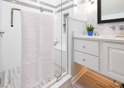 Bathroom with glass shower, white cabinets and under cabinet light.