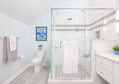 Bathroom with glass shower, toilet and white cabinets.