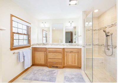 Master bathroom with wooden cabinets and a glass shower on the right.