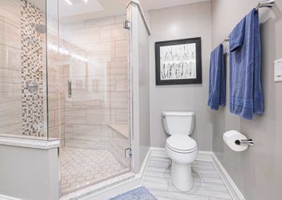 Glass corner shower with a toilet on the right.