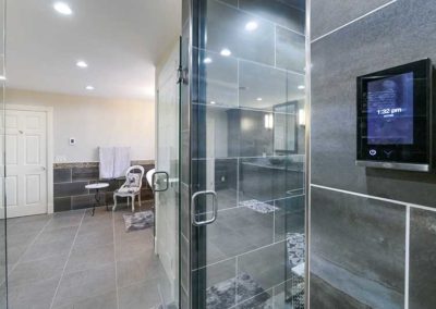 Big open space bathroom with black tiled glass shower.