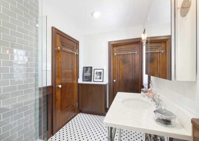 Bathroom with checkered tiled floors, marble countertop and glass shower.