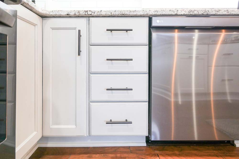 White wood kitchen cabinets with metal handles and an LG dishwasher.