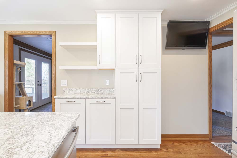 White cabinets with shelves in a kitchen with a tiny countertop space.
