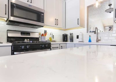 White quartz countertops on an island in a kitchen.