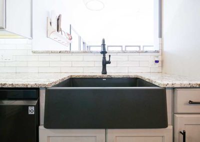 Granite kitchen countertops near a big black sink.