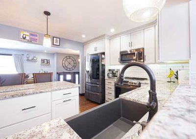 Granite countertop in a kitchen with white cabinets and a black sink with a modern black faucet.