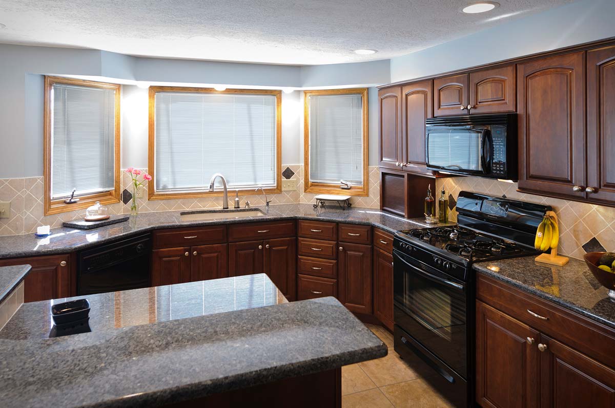 Kitchen with dark wood cabinets and black granite countertops.