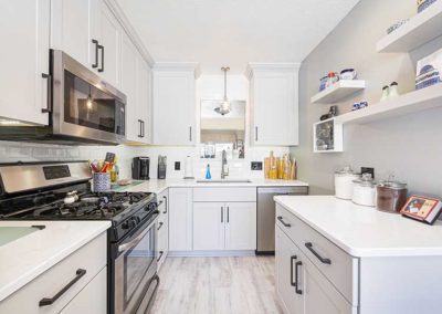 Small kitchen with smart space organization with white cabinets and quartz countertops.