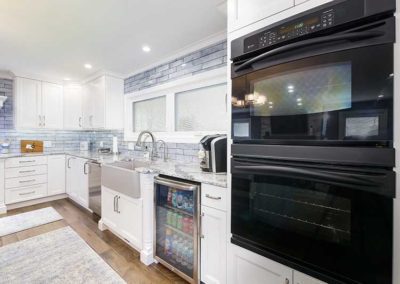 Open space kitchen with white cabinets, granite countertops and easily accessible appliances.