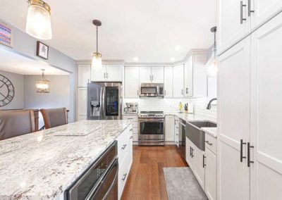 Open space kitchen with white cabinets and granite countertops.