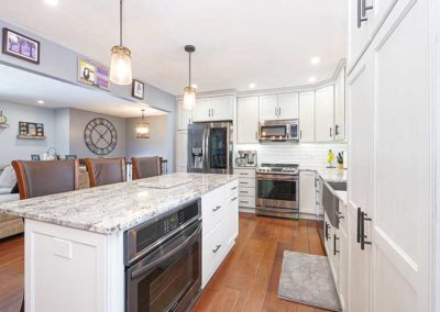 Big open space kitchen with white cabinets and granite countertops.