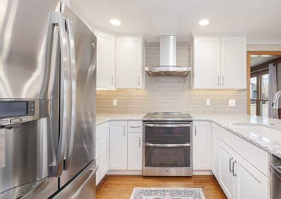 Kitchen with white cabinets, grey granite countertops and metal appliances.