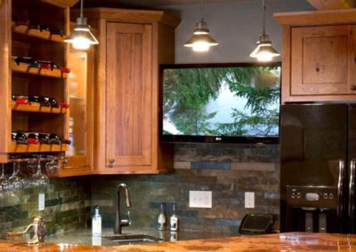 Custom cutout for a TV in a bar with wood cabinets and granite countertop.