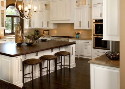 Gorgeous open space concept kitchen with white ceiling tall cabinets and dark wooden countertop island.