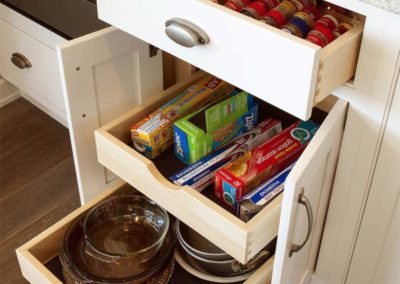 Unique and useful storage space inside kitchen cabinet drawer for spices with extra storage for big pots and pans underneath.